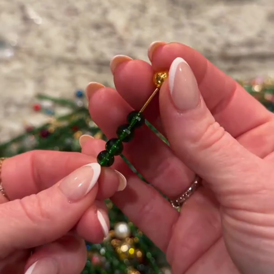 Threading beads onto a green wire branch